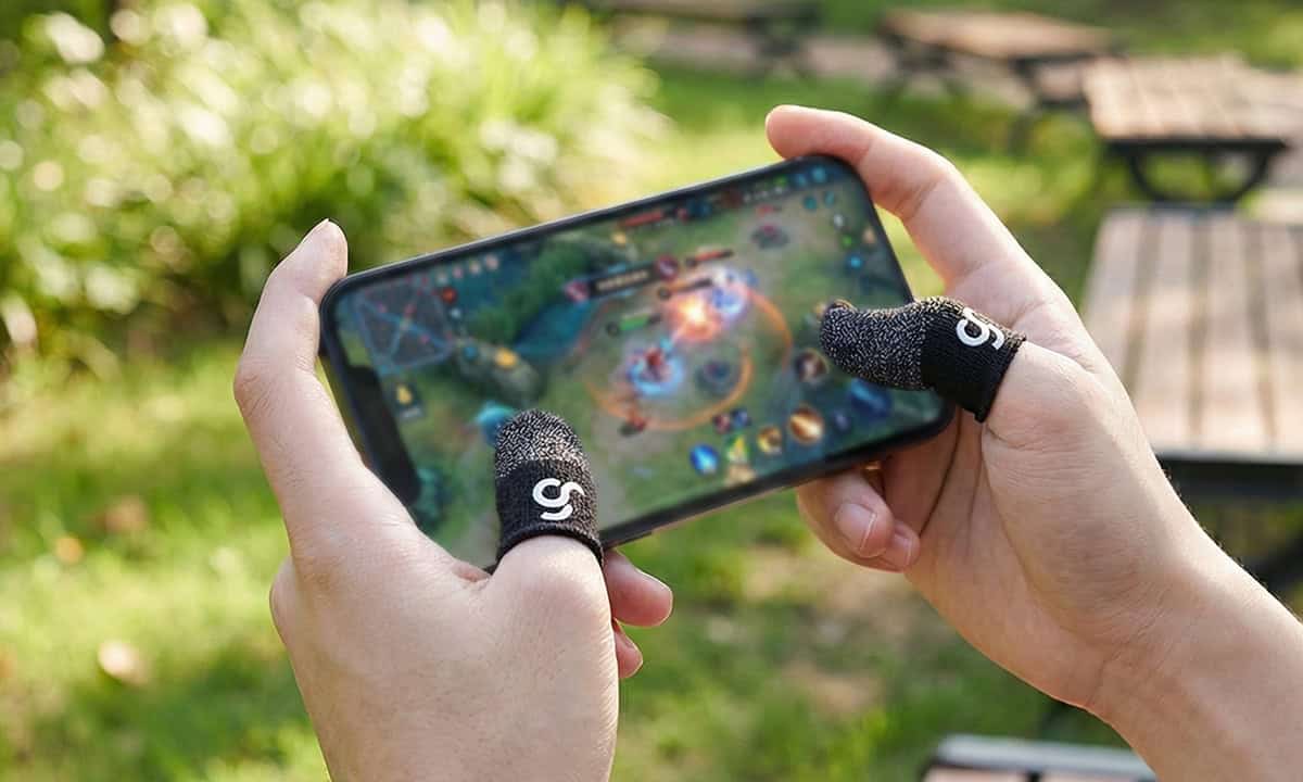 Oyuncu, Mobile oyun oynarken GamRaider eldiven kullanıyor, dış mekanda oyun keyfi.